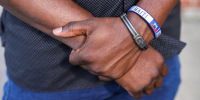 Two arms crossed over one another, a bracelet with the text "Haiti" on it is worn on his wrist