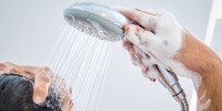 A man stands in the shower at home and washes his hair