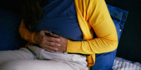 Person Experiencing Abdominal Discomfort While Resting at Home