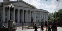 Pedestrians walk past the Treasury building in Washington, D.C.