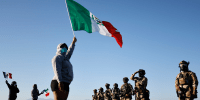 A protester holds a Mexican flag.