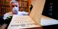 A restorer shows an old book with holes in its pages due