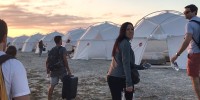 People walk towards tents at sunset