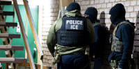 ICE agents outside a residential door.
