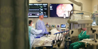 Dr. John Gaetano performs a colonoscopy on Mike Lowe in a hospital room