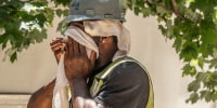 A construction worker wipes sweat from his face as he  to stay cool 