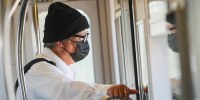 A person wears a black surgical mask on a train