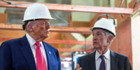 Donald Trump and Jerome Powell stand next to each other wearing white hard hats, as Jerome speaks