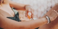 A woman spritzes sun screen on her arm during vacations