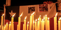 Candles burn during a vigil backdropped with a Chilean national flag and victims of a mine collapse