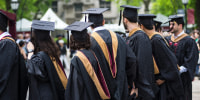 The backs of graduates wearing gowns and caps