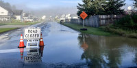 Cones and a road closed sign on a flooded residential street