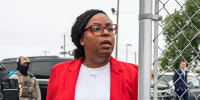 LaMonica McIver walks past a chainlink fence gate outside