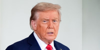 Donald Trump stands near a doorway outside