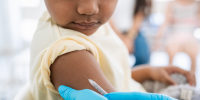 Young boy getting a shot at doctor's office and looking at needle