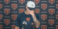 Tyson Bagent puts his hand over his face while standing at a podium