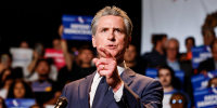 Gavin Newsom speaks at a podium with a red sign on it that reads "Election Rigging Response Act"