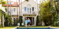 Senior couple walking by swimming pool in back yard