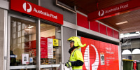 Image: A postman enters an Australia Post store