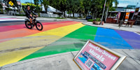 A biker rides through a rainbow-painted crosswalk