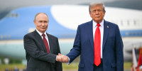Vladimir Putin and Donald Trump shake hands.