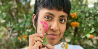 Catalina "Xochitl" Santiago holds a pink flower near her cheek