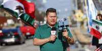 Mario Guevara holding a microphone and an iPhone via a tripod
