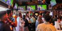 Fans watch Super Bowl at a bar.