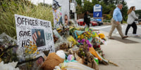 Pedestrians pass a memorial for officer David Rose at the CDC headquarters