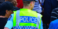 A New Zealand police officer walks in a crowd of people. 