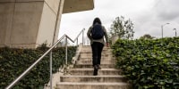 Rear view of a university student walking up the stairs