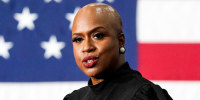 Ayanna Pressley speaks at a podium with an American flag backdrop