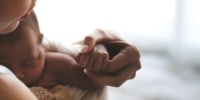 Close up Mother holding hands Asian female newborn baby  and sunlight in the morning. Cute little girl  three weeks old. Health, care, love, relationship concept.