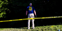 An FBI agent stands in an area behind Utah Valley University where evidence was collected