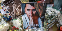 Pictures of Charlie Kirk next to bouquets of flowers on the grass