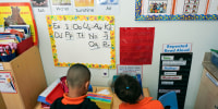 Two children, backs to camera, look at a pre-school decorated wall