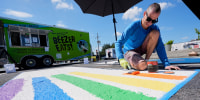 A person paints colored strips in a parking spot outside