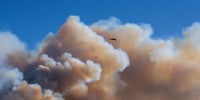 A helicopter flies above clouds of smoke