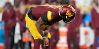 Jayden Daniels #5 of the Washington Commanders reacts after being hit 