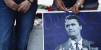 Jordyn Hackner, president of Turning Point USA's University of Houston chapter, and Lizbeth Aguilar, stand with a poster of Charlie Kirk at a vigil on the university campus in Houston, Texas, on Sept. 11, 2025.  