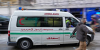 A man runs next to an ambulance arriving at the site of an Israeli airstrike that targeted a building in Beirut, Lebanon, Tuesday, Nov. 26, 2024.