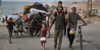 People walk on a road with their belongings