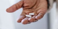 Close-up of unrecognizable black woman holding pills and glass of water