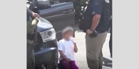 A young girl is surrounded by law enforcement agents outside a house in Leominster, Mass.
