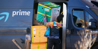 An Amazon Prime delivery person lifts packages while making a stop 
