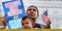 A person holds a sign that reads, "American Born Children Are American Children"