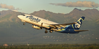 A plane takes off against the backdrop of the Chugach Mountains