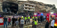 Rescuers and first-responders stand outside a damaged building following an overnight Israeli strike in Al-Msayleh area in southern Lebanon on October 11, 2025.