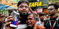 Two men crying as one shows a picture of a fire accident victim on his mobile phone