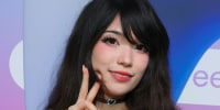 Emiru smiles and throws up a peace sign